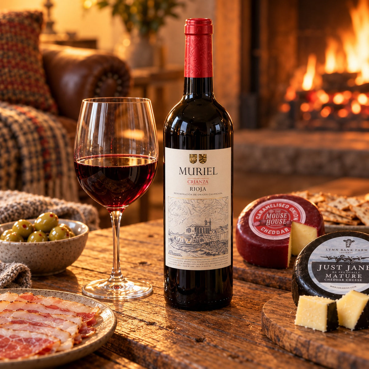 Muriel Crianza Rioja with a poured glass, cheese and olives by the fire
