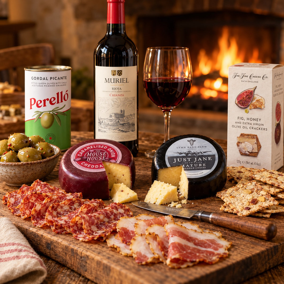 A board by the fire with the hamper's Muriel Rioja, two cheeses, salami and lomo, Perello olives and fig and honey crackers