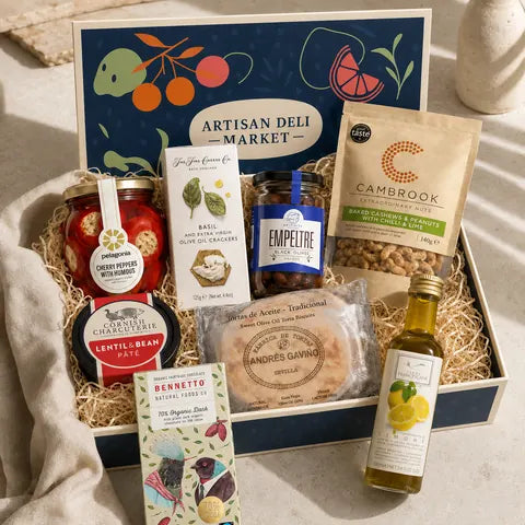 An open Presentation box printed with oranges and leaves, filled with jars, crackers and chocolate on straw.